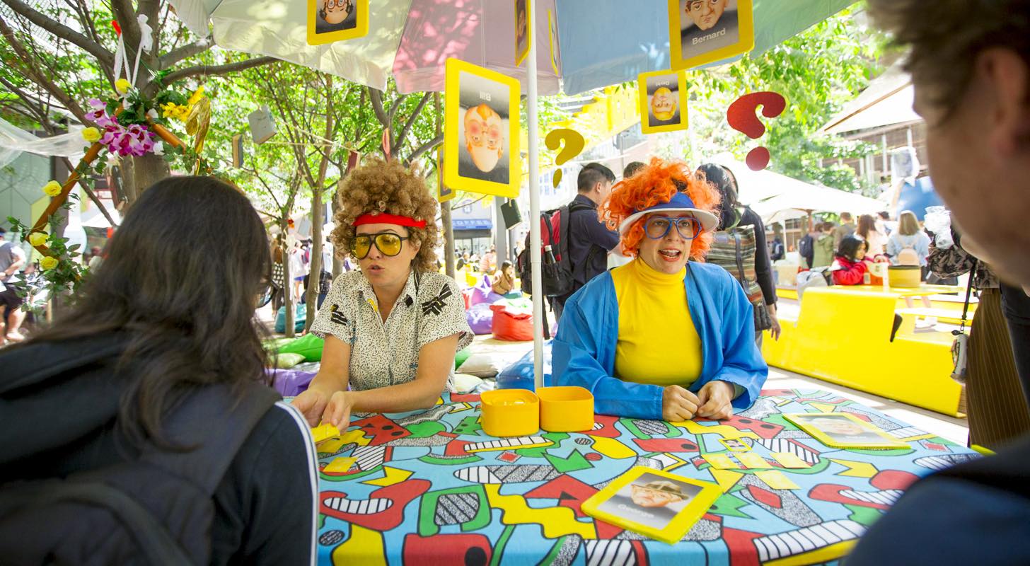 Two students in fancy dress sitting at an information booth.